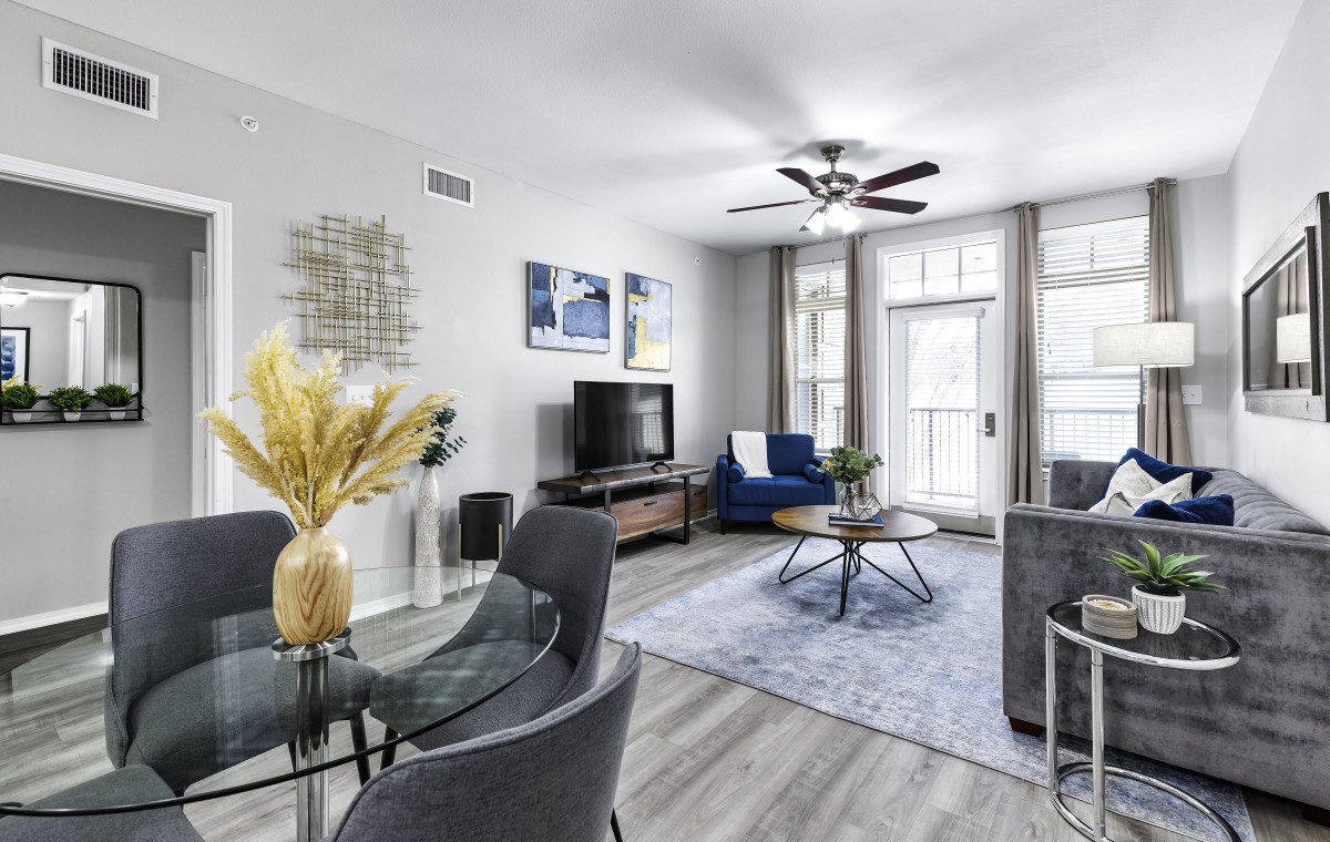 A modern living room with stylish furnishings, including a TV, circular coffee table, and decorative wall art.