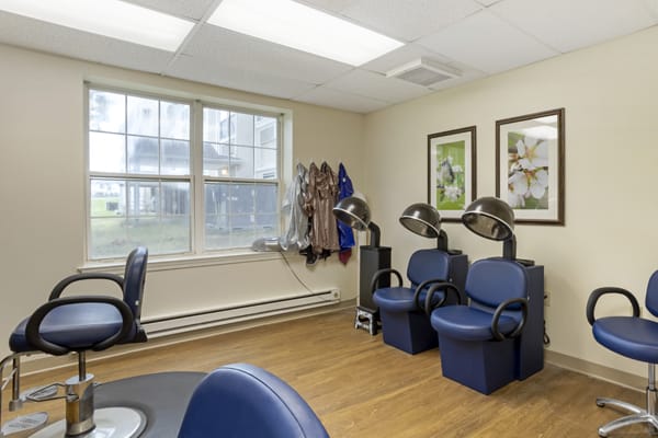 A cozy salon interior with hair drying stations and a coat rack by the window.