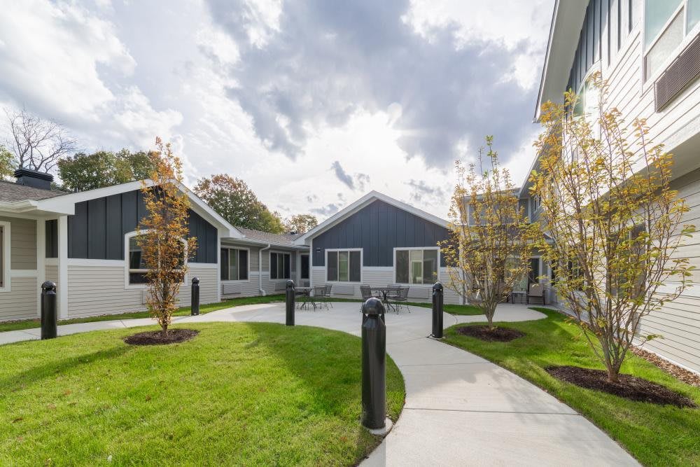 A modern residential building with well-maintained landscaping and a winding pathway under a cloudy sky.
