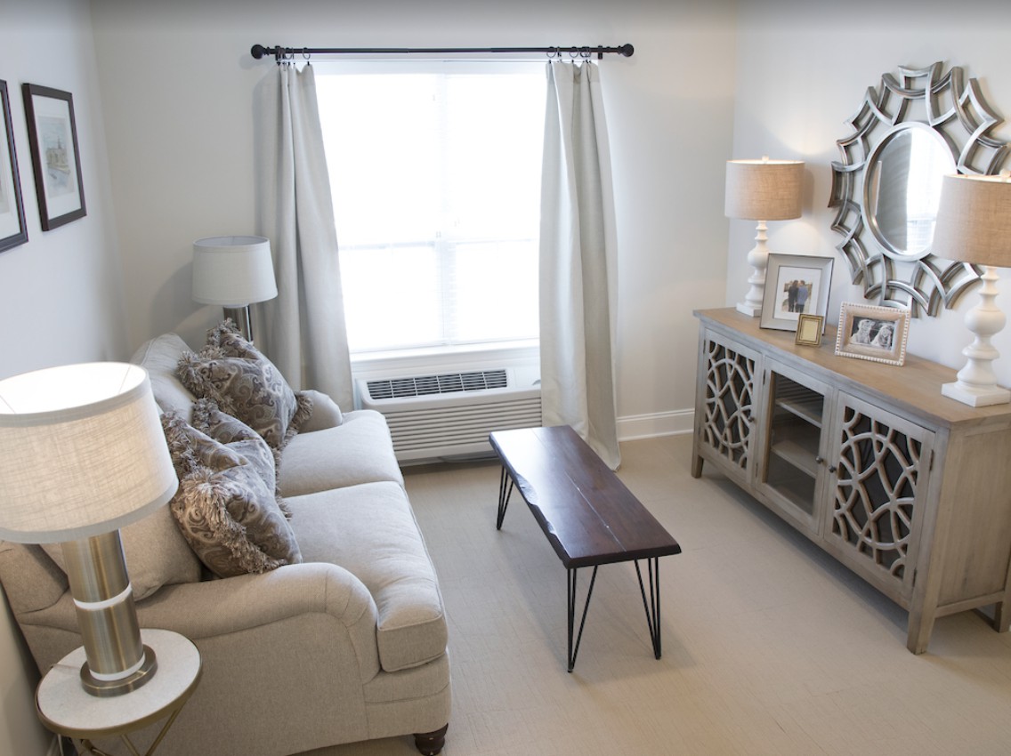 A cozy and well-lit living room with a sofa, coffee table, and decorative mirror.
