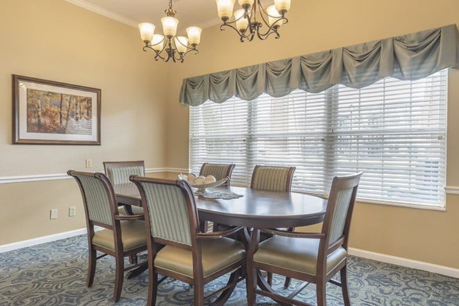 A well-decorated dining room featuring a large table, several chairs, and an elegant chandelier.