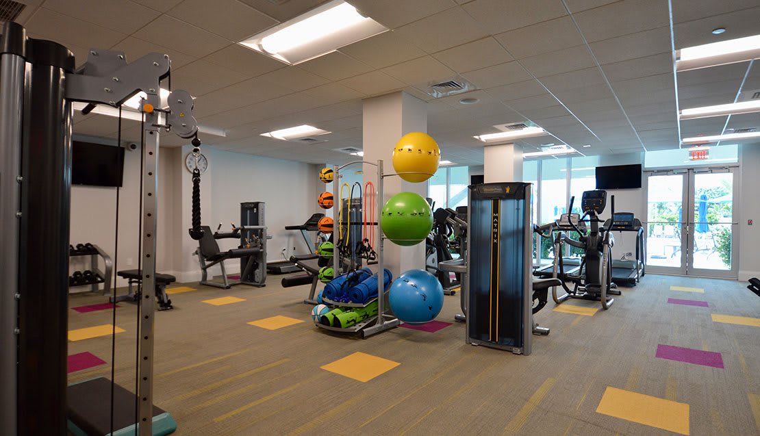A well-equipped gym with various exercise machines and colorful fitness balls.