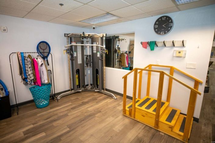 A rehabilitation room equipped with various exercise machines and tools.