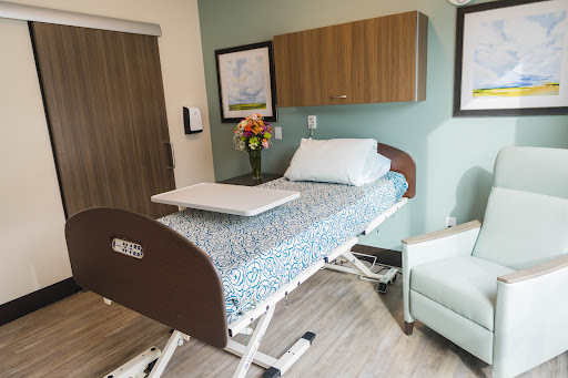 A well-designed patient room featuring a hospital bed and a comfortable seating area.