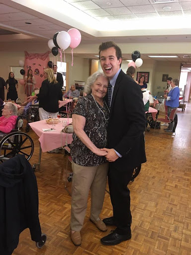 A joyful moment shared between a young man and an elderly woman at a community celebration.