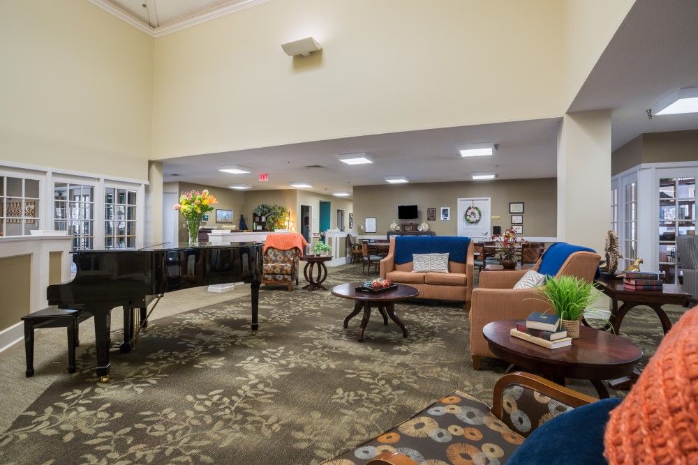 A spacious and well-decorated lounge area featuring comfortable seating and a grand piano.