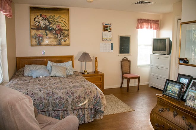 A cozy bedroom with a double bed, dresser, chair, and television.