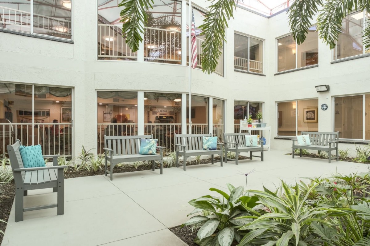 A bright indoor courtyard with benches and lush plants under a skylight.