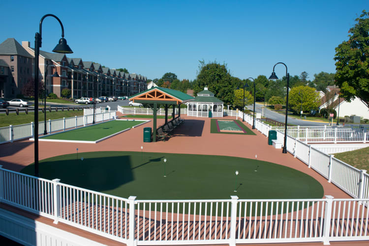 A landscaped park with a fenced recreation area featuring a pavilion and well-maintained grounds.