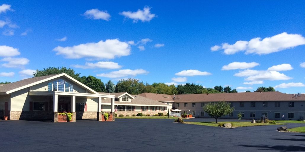 A motel with a large parking lot under a clear blue sky with a few clouds.