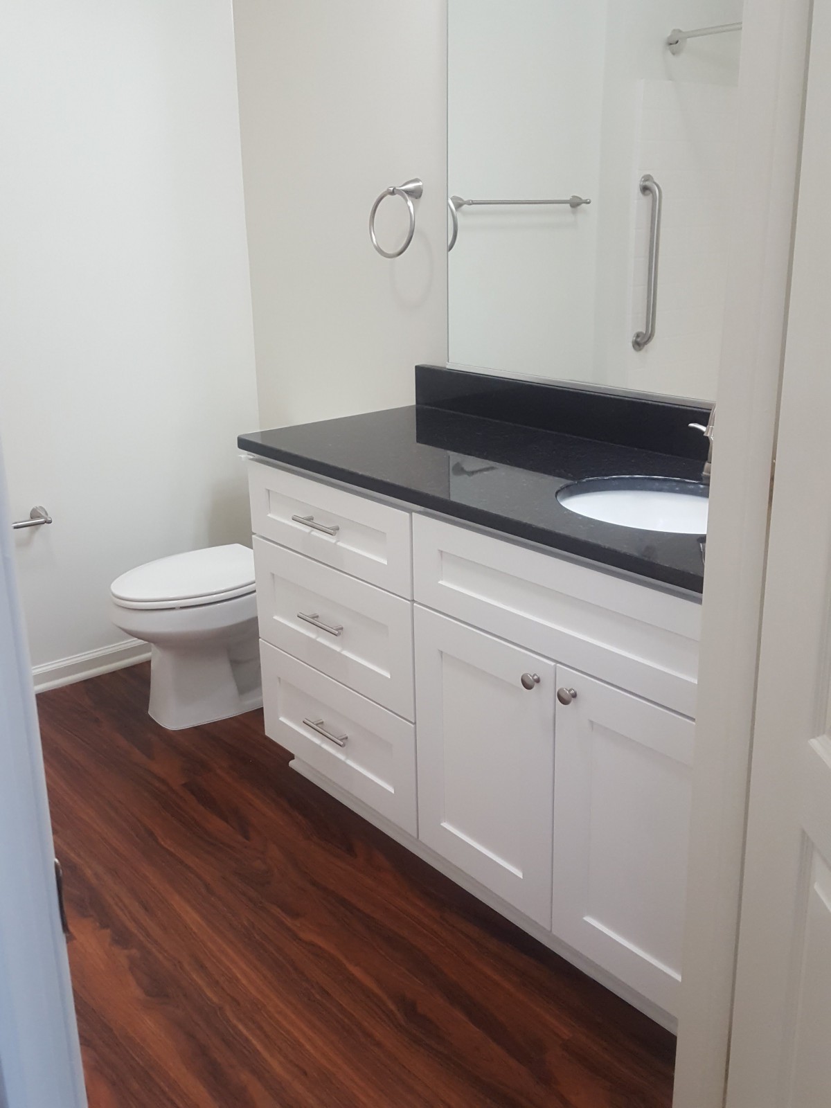 A modern bathroom with white cabinets and a granite countertop.