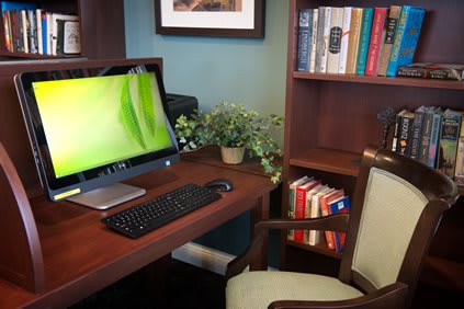 A cozy home office setup with a computer, bookshelves, and a plant.