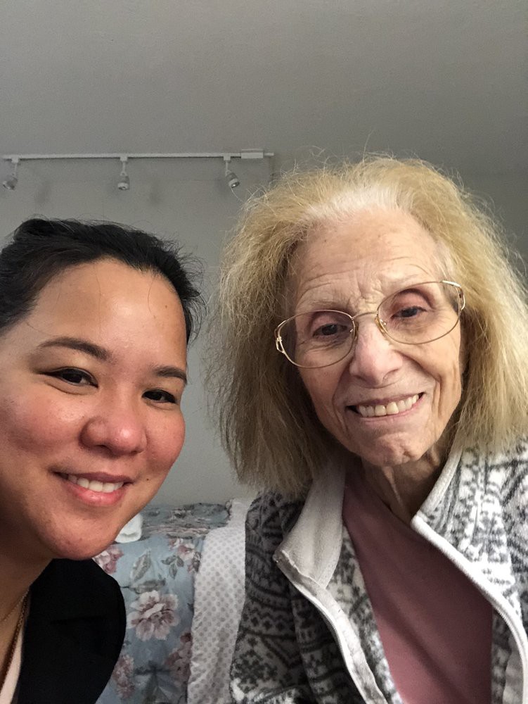 A selfie of two smiling women, one of whom is elderly, indoors.