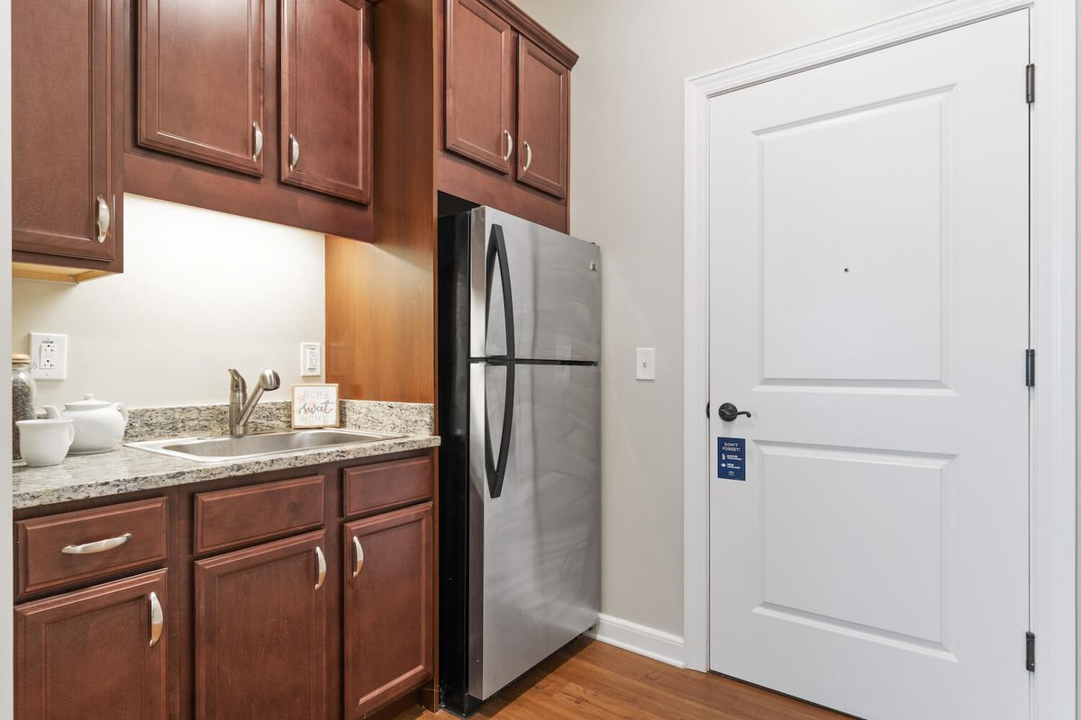 A kitchen area featuring wooden cabinets, a stainless steel refrigerator, and a countertop.