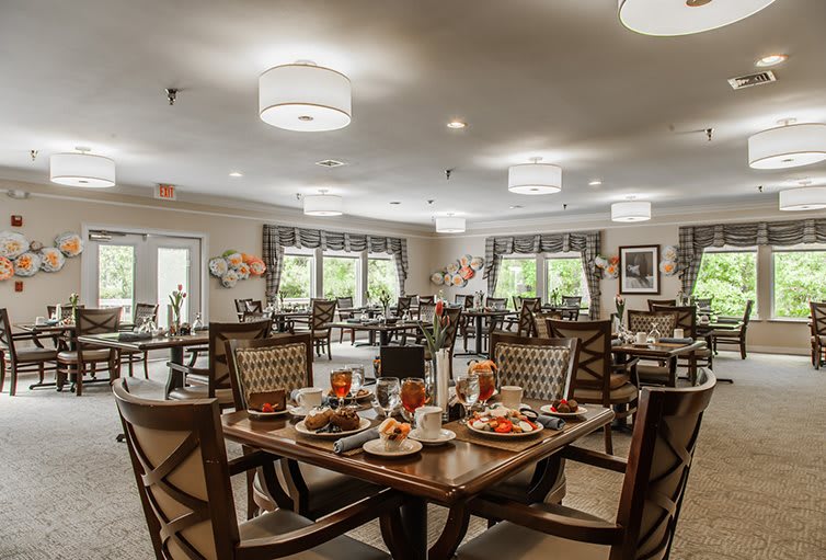 An elegantly decorated dining room with neatly arranged tables and chairs, bathed in natural light.
