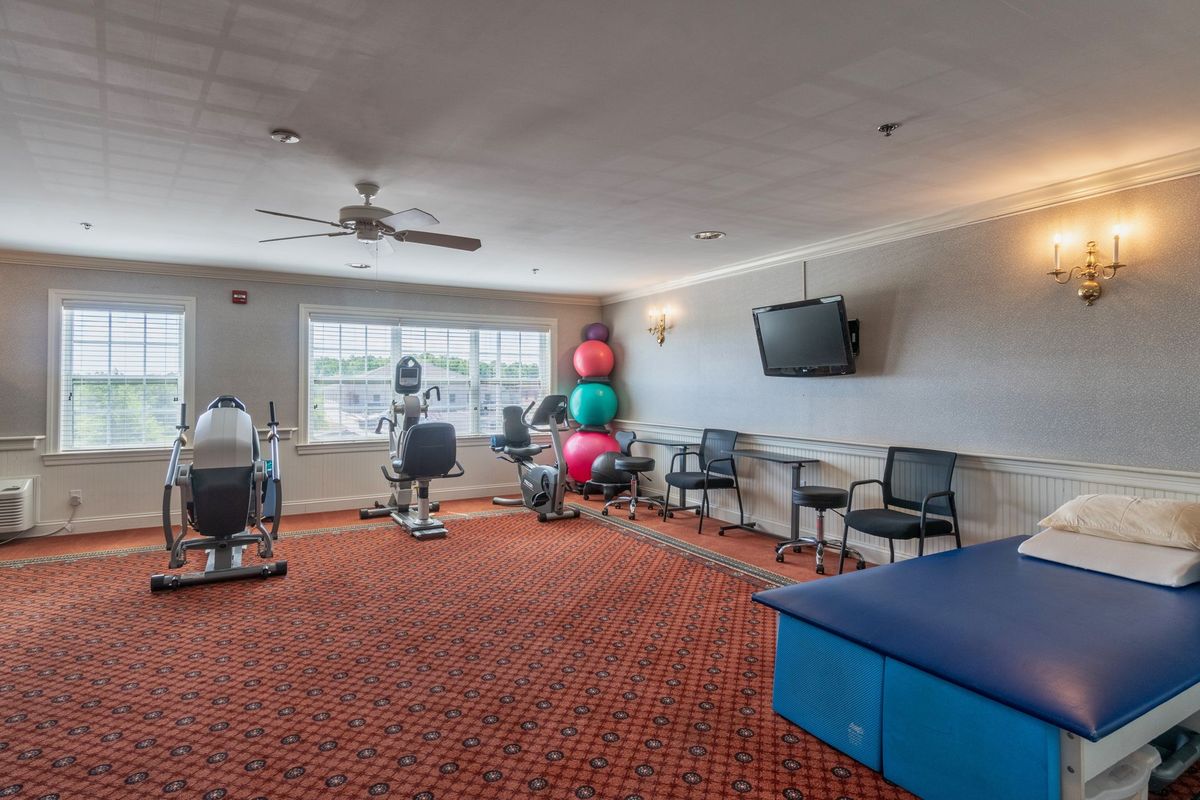 A fitness room equipped with stationary bikes, exercise balls, and a television.