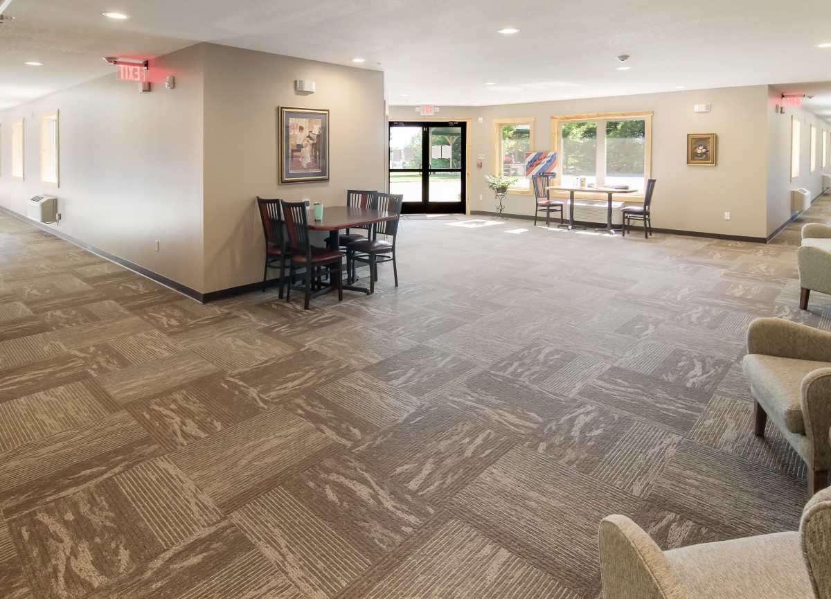 A spacious and well-lit lobby area with tables and chairs, featuring modern flooring and large windows.