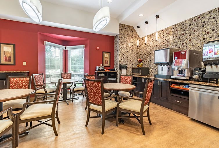 A cozy cafe interior with modern decor, featuring tables and chairs arranged around a coffee station.