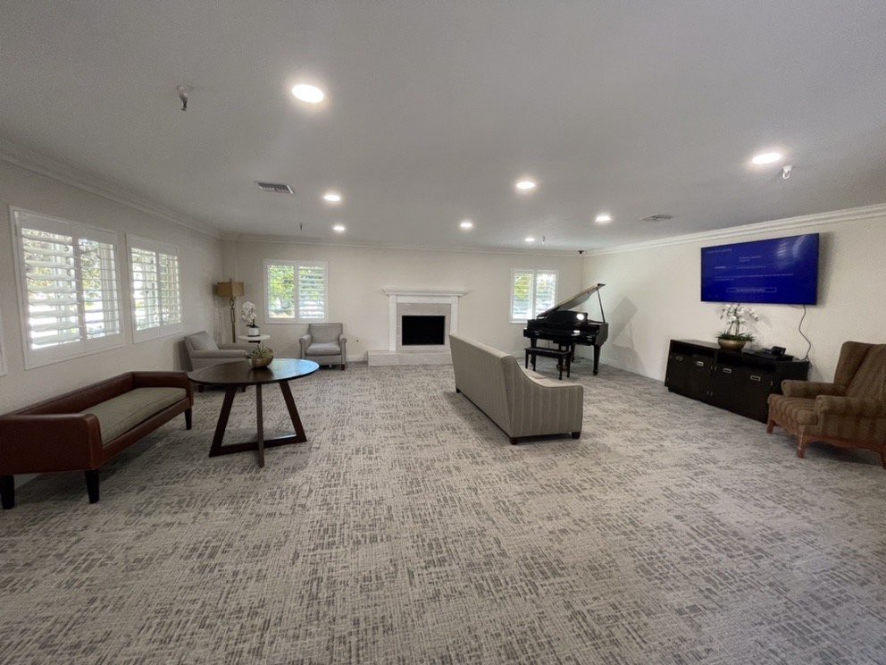 A spacious modern living room with a piano and a large television.