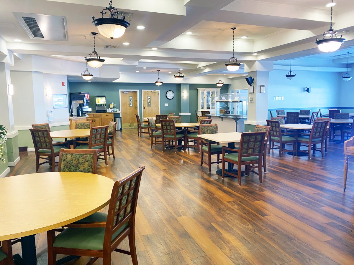 An empty dining area with wooden floors, tables, and chairs.