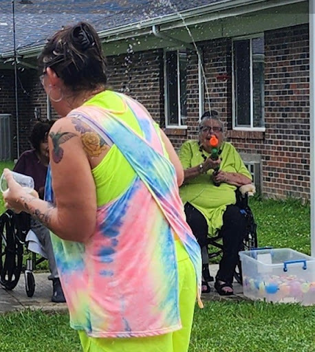 A lively outdoor activity with individuals in colorful attire, engaging with residents in wheelchairs.
