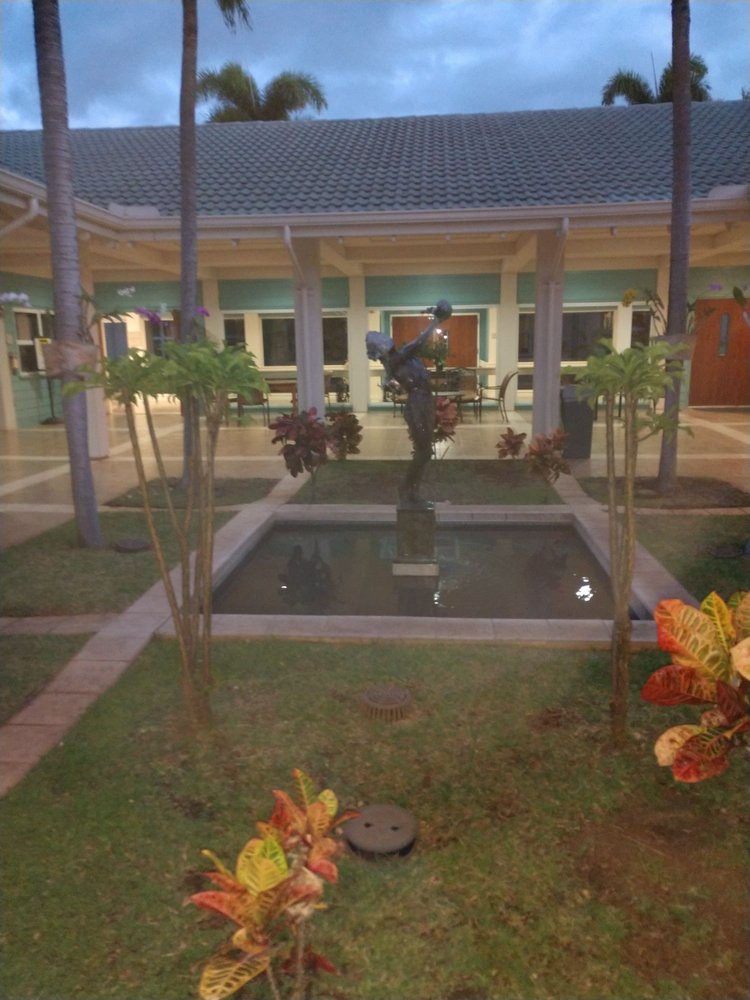 A serene courtyard at night featuring a small fountain surrounded by plants.