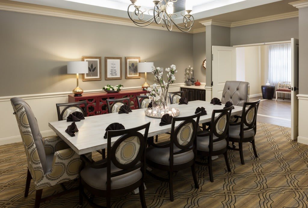 An elegantly decorated dining room featuring a long table, multiple chairs, and a chandelier.