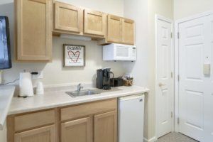 A compact kitchen area with wooden cabinets, a microwave, coffee maker, and mini fridge.
