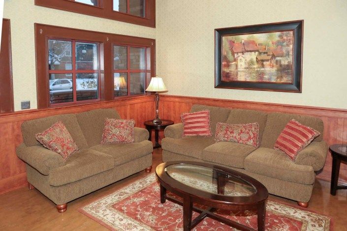 A cozy living room with brown sofas, a glass coffee table, and a patterned rug.