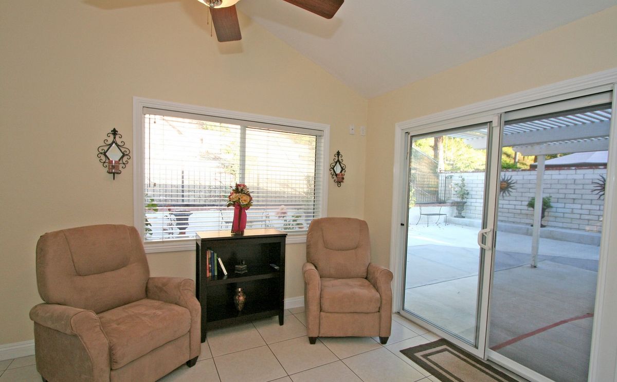 Cozy living room with two chairs, a bookshelf, and large window views.