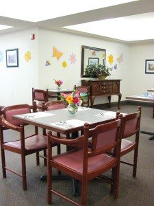 A cozy dining area with tables and chairs, decorated with flowers and wall art.