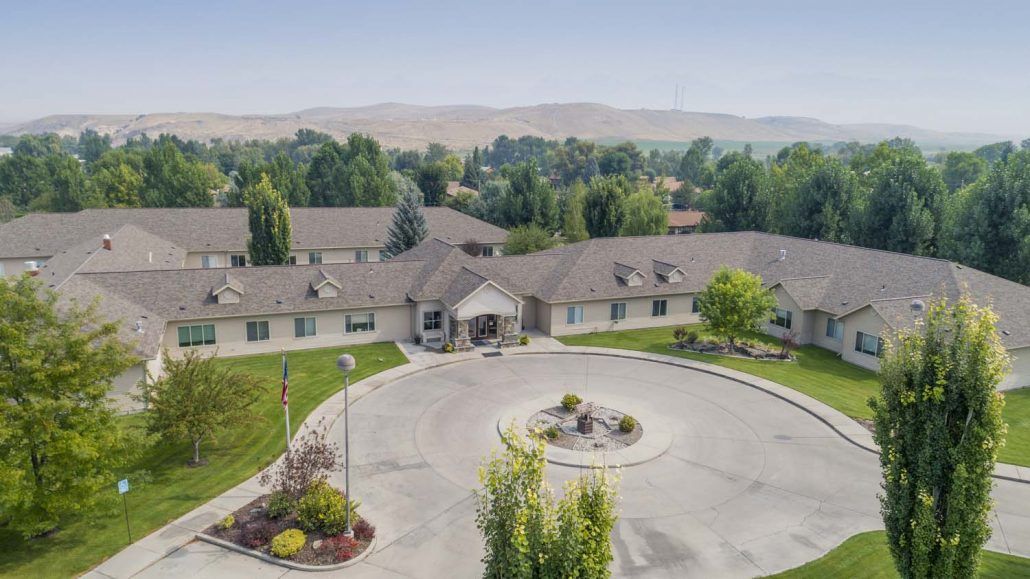 Aerial view of a large residential building with surrounding greenery and a circular driveway.