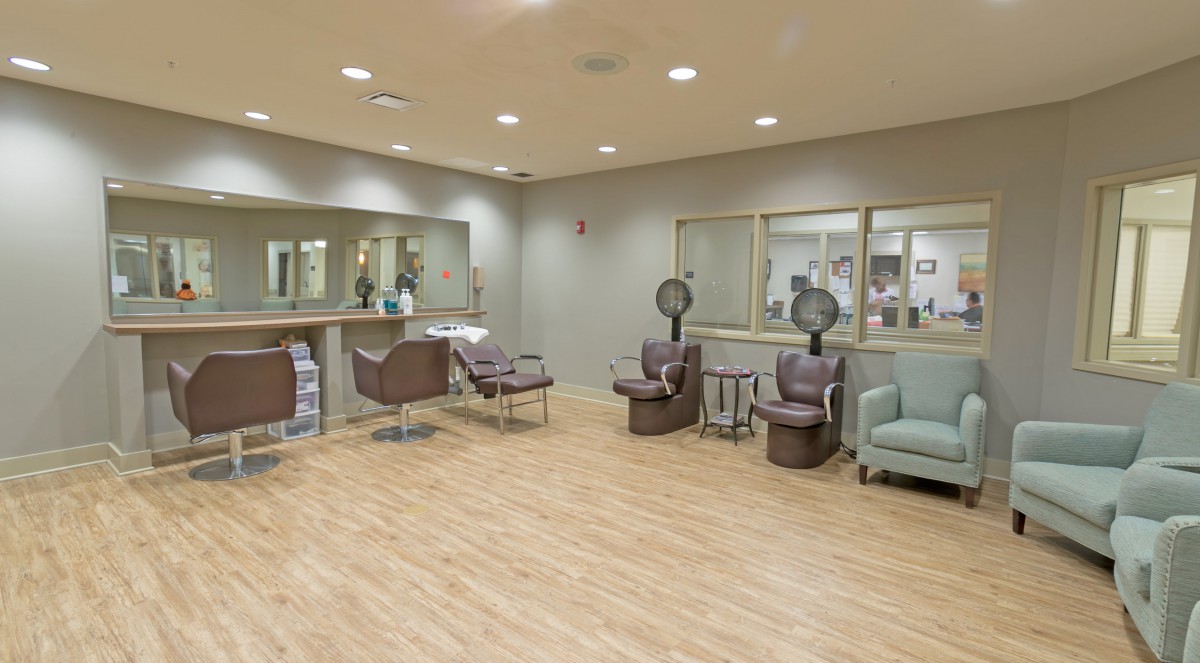 A modern and spacious hair salon with styling chairs, mirrors, and hair dryers.