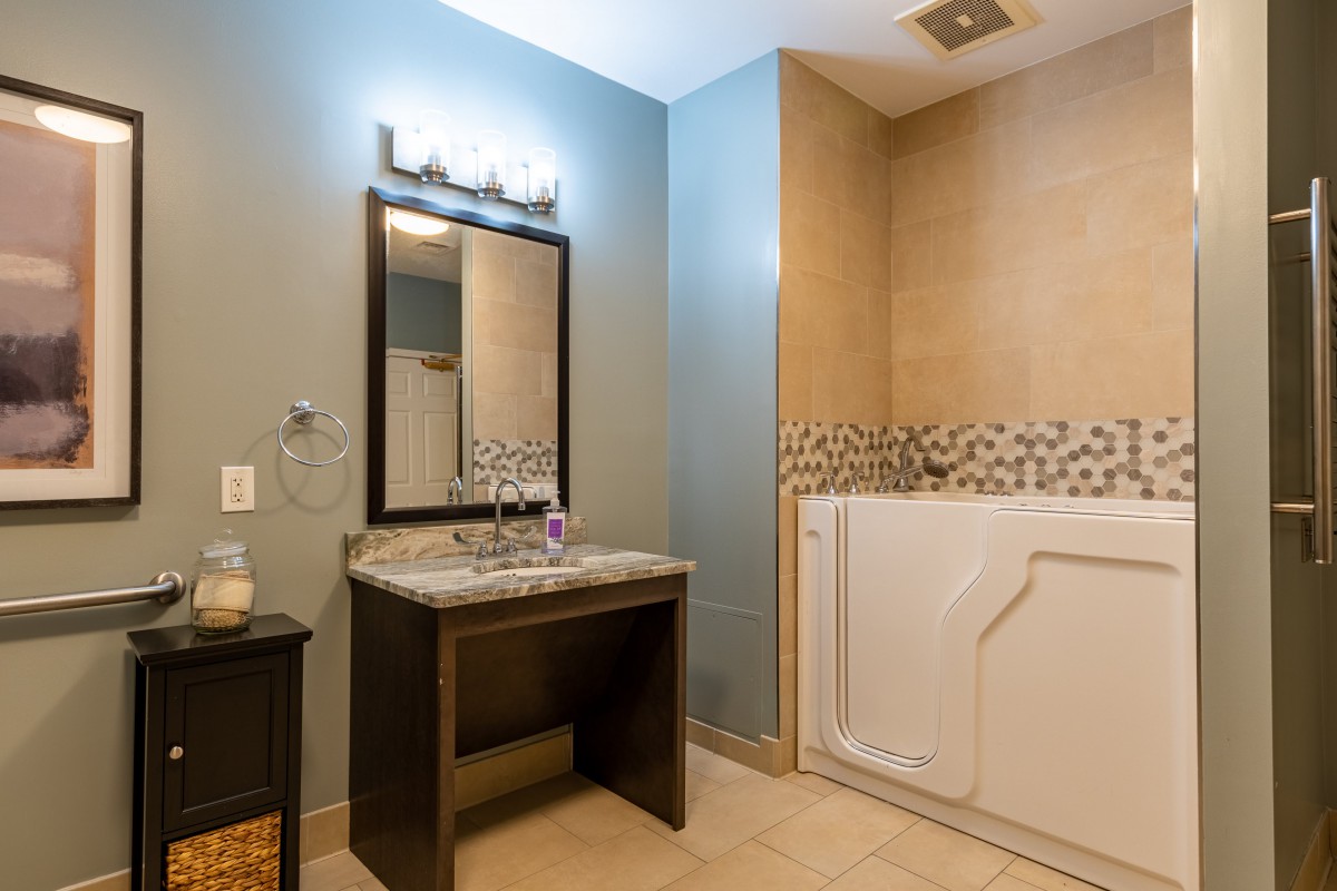 A modern bathroom featuring a vanity with a mirror and a walk-in tub.