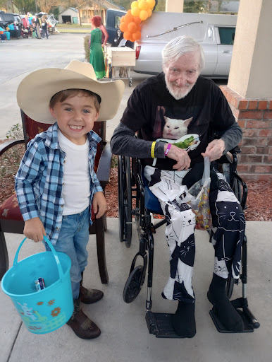 A young boy in a cowboy hat shares a joyful moment with an elderly man, both smiling and enjoying their time together.