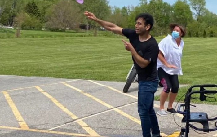 A person is enthusiastically tossing a balloon during an outdoor group activity.