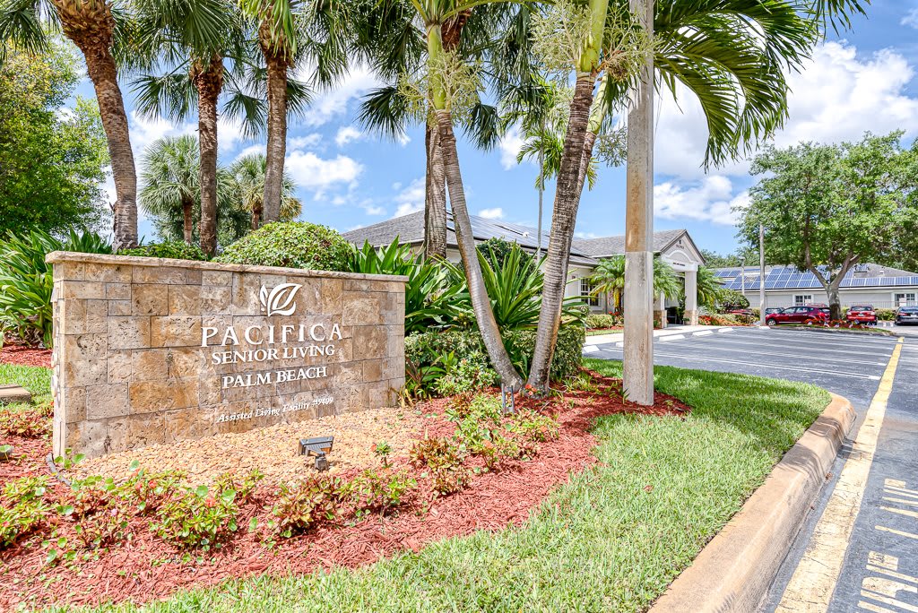 Entrance to a residential community with palm trees and lush landscaping.