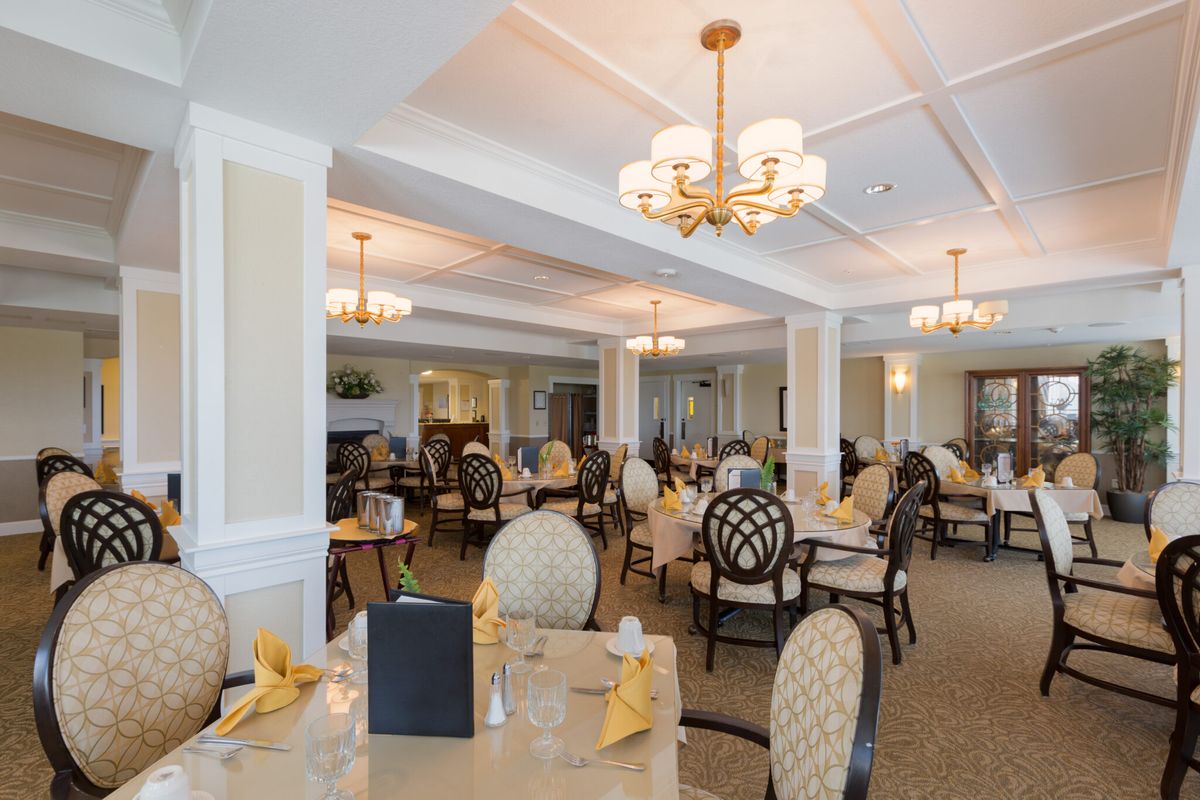 An elegant dining room with multiple tables and chandeliers.