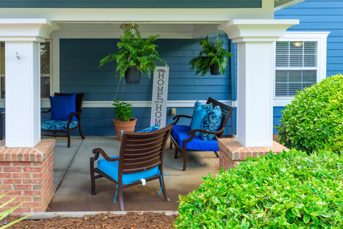 A cozy patio with blue cushioned seating and lush greenery.