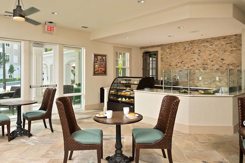 A cozy cafe interior with tables and chairs, featuring a display case and counter.