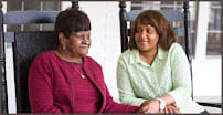 Two women sitting together, engaged in conversation and smiling.