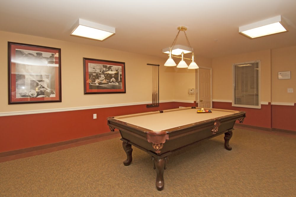 A billiards room featuring a pool table with overhead lighting and wall decorations.
