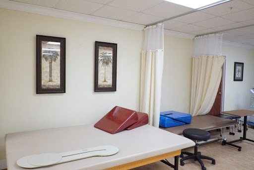 A well-equipped therapy room featuring treatment tables and privacy curtains.
