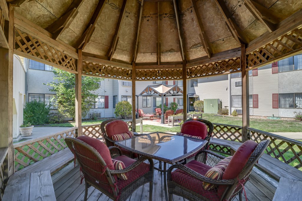 A cozy gazebo with patio furniture offering a garden view.