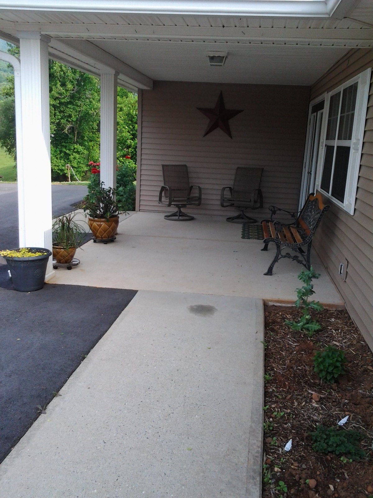 A cozy porch with chairs, benches, and decorative plants.