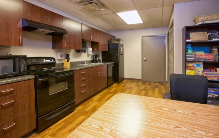 A modern kitchen with wooden cabinets, stainless steel appliances, and a hardwood floor.