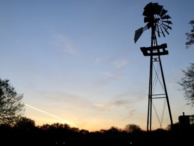 A silhouette of a windmill against a sunset sky.