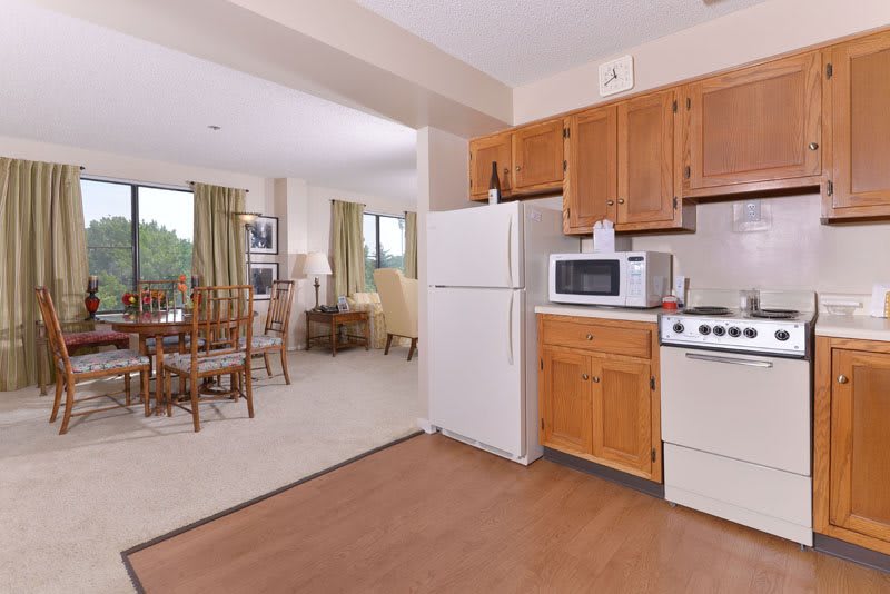 An open-layout kitchen and dining area featuring wooden cabinets, a refrigerator, stove, and microwave.
