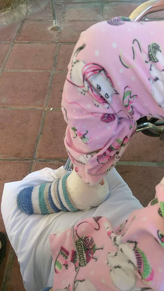 Child wearing pink pajamas and striped socks standing on tiled floor.