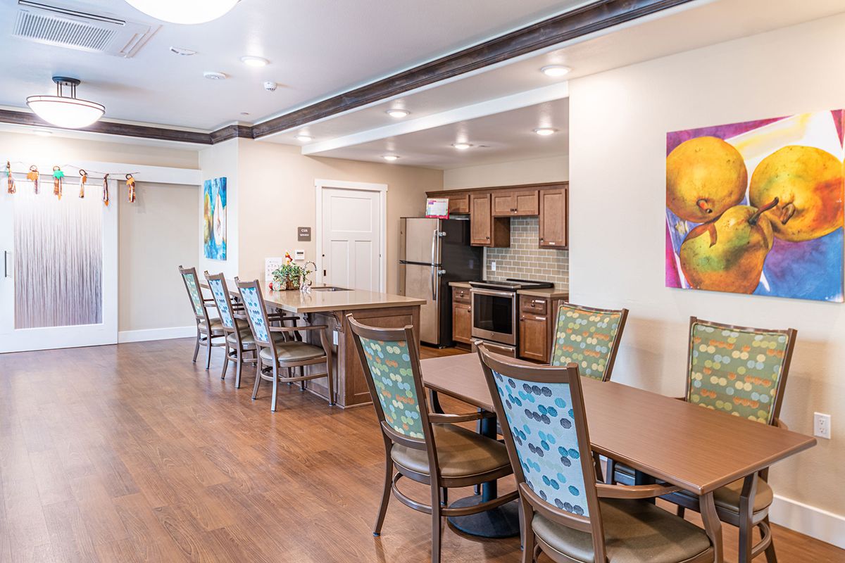 A modern dining area with a kitchen, featuring stylish chairs and vibrant artwork.